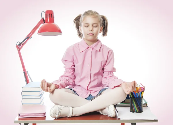 Schoolgirl meditating on the desk — Stock Photo, Image