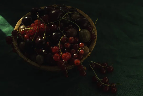 Olgun sulu kirazlar sepetin içinde siyah bir arka planda.