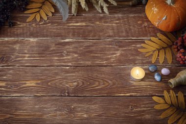Autumn authentic layout on wooden backdrop with dry leaves, pumpkin, ashberry, agate gemstones, bottle, candle and feather, copy space, selective focus. clipart