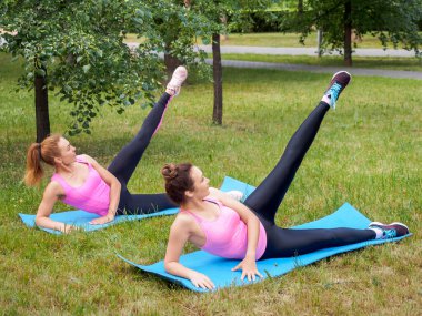 Açık hava takibi. Yazın halk parkında iki beyaz kadın yan tekme atıyor, seçici bir şekilde.