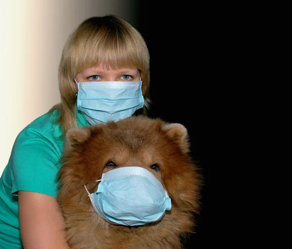 Mujer joven con máscara de protección contra el virus y un hermoso perro pelirrojo con una máscara — Foto de Stock