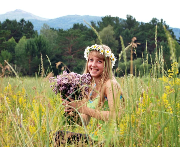 Gadis cantik dengan karangan bunga di padang rumput — Stok Foto