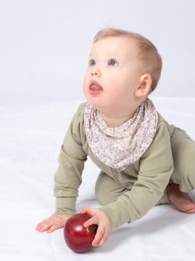 Güzel bebek bir elma tutuyor, beyaz bir arka plan.