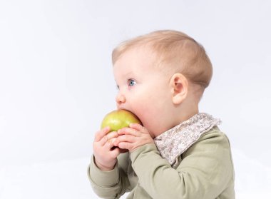 Güzel bebek bir elma tutuyor, beyaz bir arka plan.