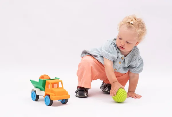 Liebenswert Baby Girl Plays Mit Spielzeug Auf Einem Weißen Hintergrund lizenzfreie Stockfotos