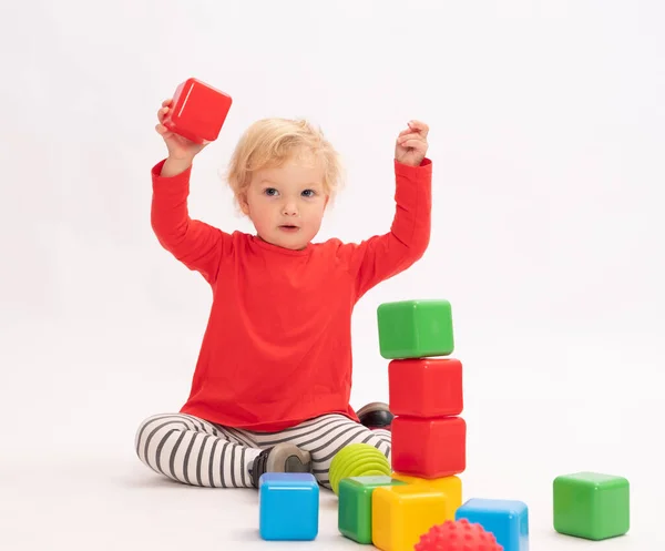 Nettes Kleines Mädchen Baut Einen Turm Aus Bunten Würfeln Weiß lizenzfreie Stockbilder