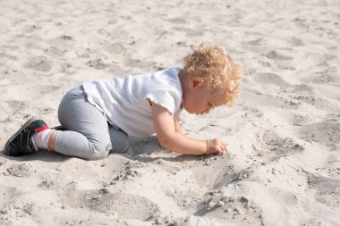 Güzel bebek kumsalda kumla oynuyor