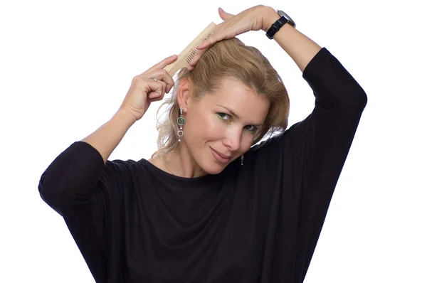 Pretty blond woman is combing her hair Stock Image