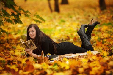 Parkta kitap okuyan genç bir kadın.