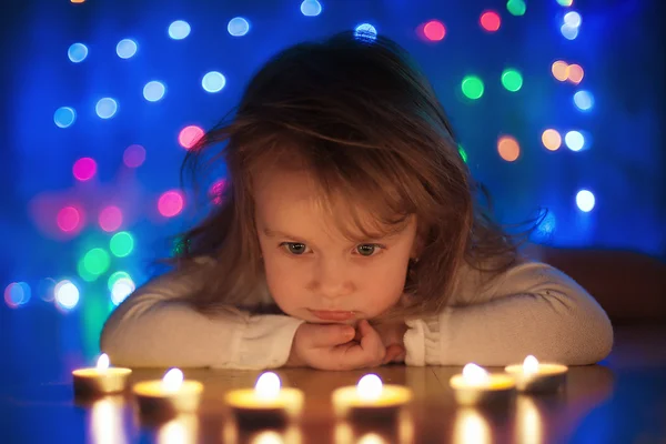 Klein meisje op zoek naar kaarsen branden — Stockfoto