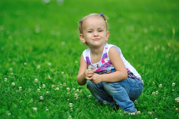 Liten flicka sitter på gräset — Stockfoto