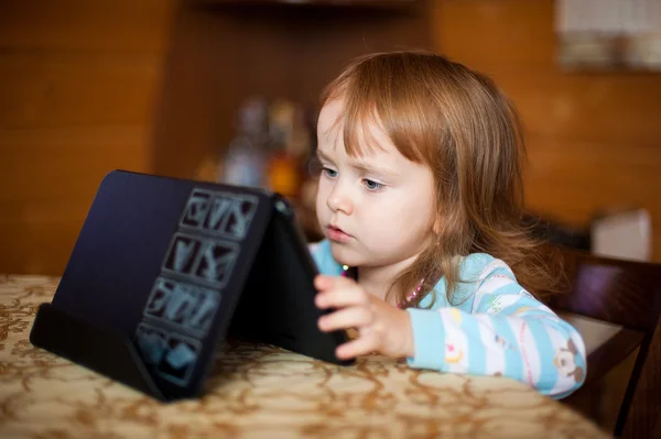 Small girl at the table with computer tablet