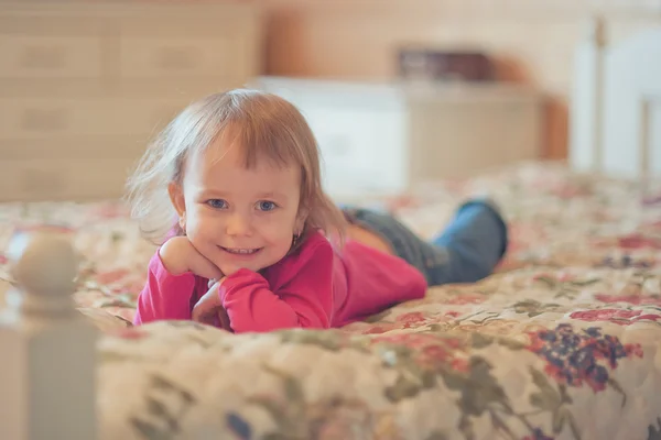 Девочка лежит на кровати — стоковое фото