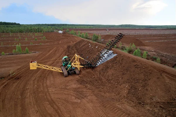 Peat extraction site. Harvester at collecting peat on peatlands. Mining and harvesting peatland. Area drained of the mire are used for peat extraction. Drainage and destruction of peat bogs.