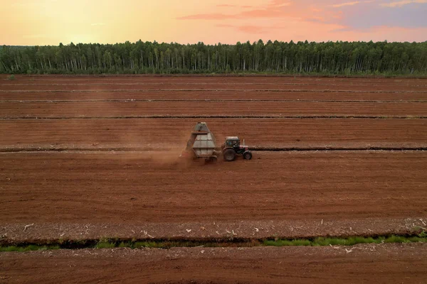 Peat Harvester Tractor on Collecting Extracting Peat. Mining and harvesting peatland. Area drained of the mire are used for peat extraction. Drainage and destruction of peat bogs.