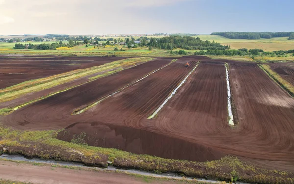 Peat extraction site. Harvester at collecting peat on peatlands. Mining and harvesting peatland. Area drained of the mire are used for peat extraction. Drainage and destruction of peat bogs.