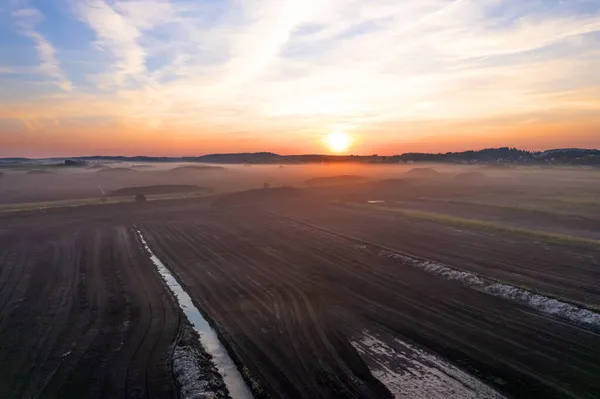 Peat extraction site in fog on sunset. Collecting peat on peatlands. Mining and harvesting peatland. Area drained of the mire are used for peat extraction. Drainage and destruction of peat bogs.