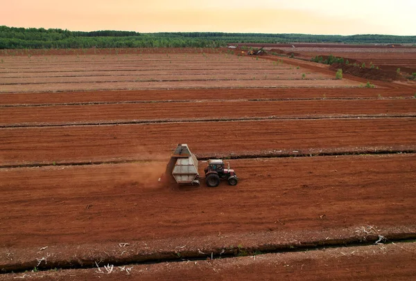 Peat Harvester Tractor on Collecting Extracting Peat. Mining and harvesting peatland. Area drained of the mire are used for peat extraction. Drainage and destruction of peat bogs.