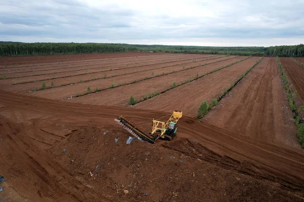 Peat harvesting field. Peat mining machine at peatland Harvester on Collecting Extracting Peat. Soft focus.