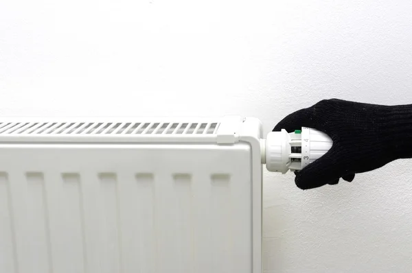 Heating radiator in cold house with arm on valve — Stock Photo, Image