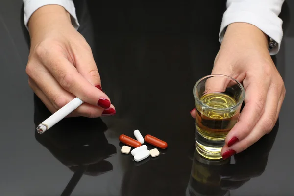 Woman hold whiskey and cigarette in hands and drugs on table — Stock Photo, Image