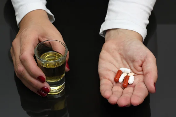 Mujer sostener whisky y pastillas en las manos — Foto de Stock