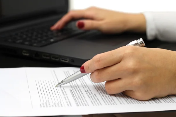 Close up of female business hands working on document and lapto Stock Picture