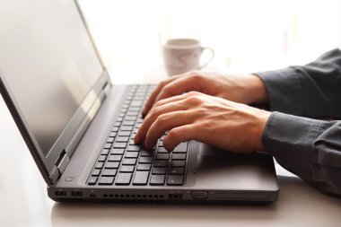 Ofiste dizüstü bilgisayarda yazan bir işadamı.