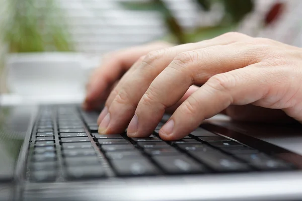 Close-up van de mens te typen op laptop in kantoor met een kopje koffie in — Stockfoto