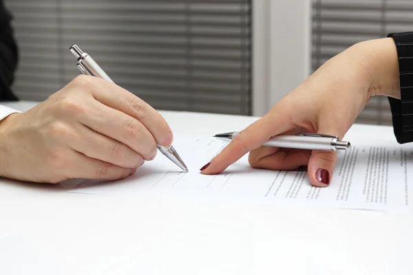 Geschäftsfrau zeigt mit Finger auf Papier, um Vertrag zu unterzeichnen Stockbild
