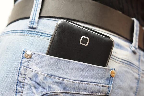 Большой мобильный телефон в женском кармане джинсов — стоковое фото