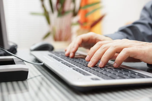 Homem está digitando no teclado em casa — Fotografia de Stock