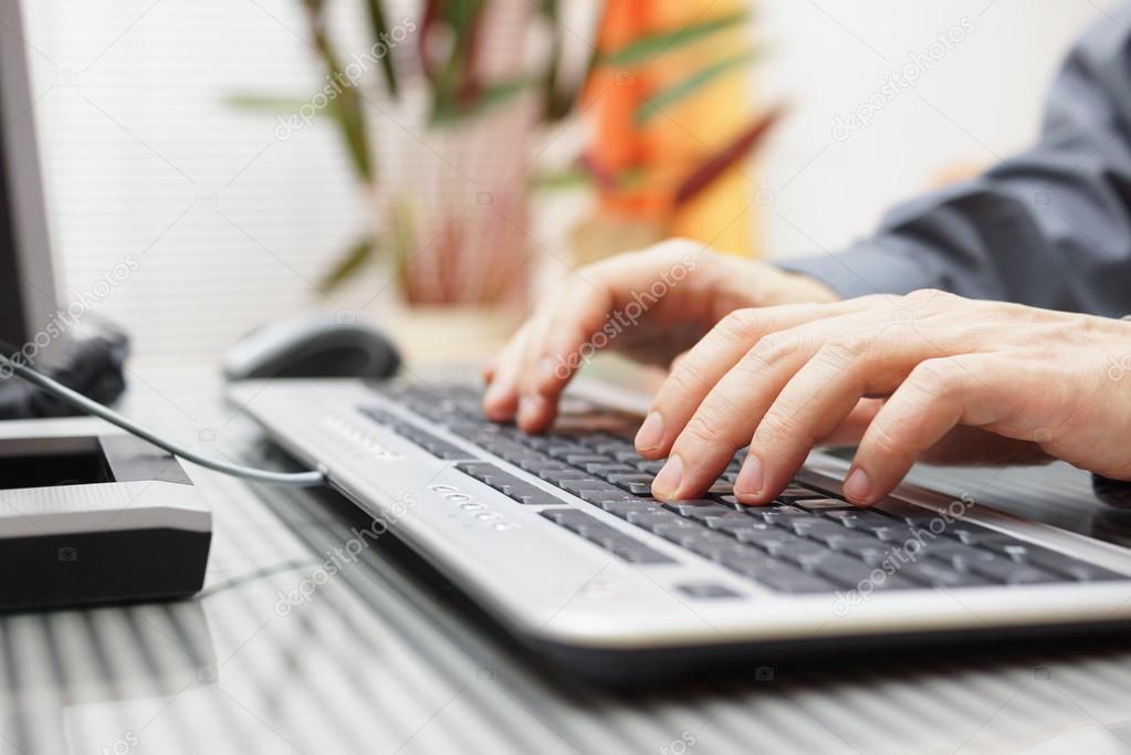 man  is typing on keyboard at home