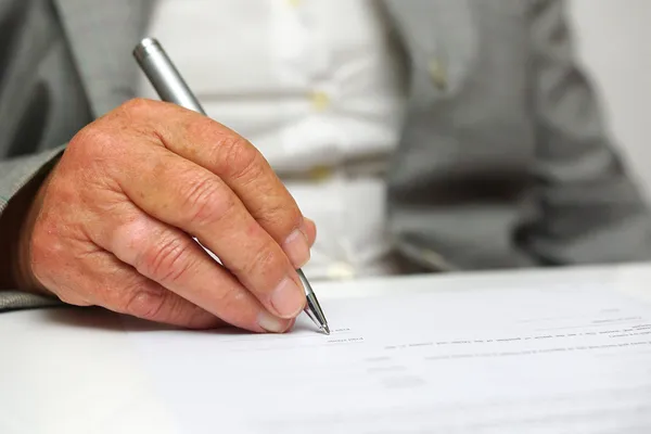 Ältere Frau unterschreibt das Dokument — Stockfoto