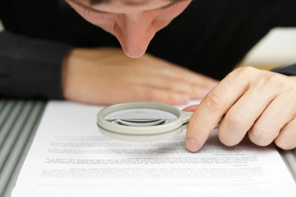 Empresario mirando a través de una lupa para documentar — Foto de Stock