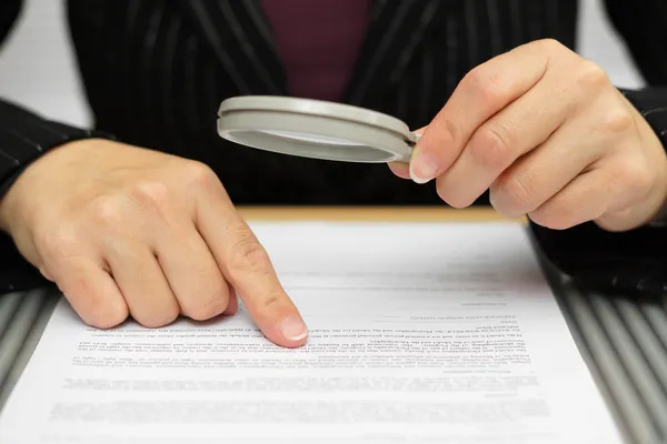 Zakenvrouw kijken door een vergrootglas te contracteren — Stockfoto