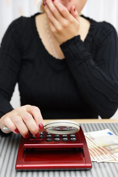 Woman watching sum on calculator with magnifying glass and cant — Stock Photo, Image