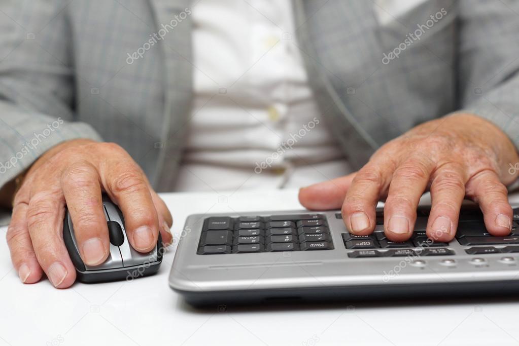 very old woman typing on keyboard and using mouse