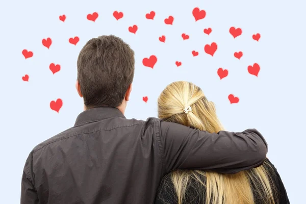Vista posterior de la joven pareja (hombre y mujer) enamorados de corazones ar — Foto de Stock