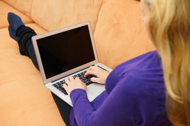 Kanepede dizüstü bilgisayar kullanan genç bir kadının yakın çekimi