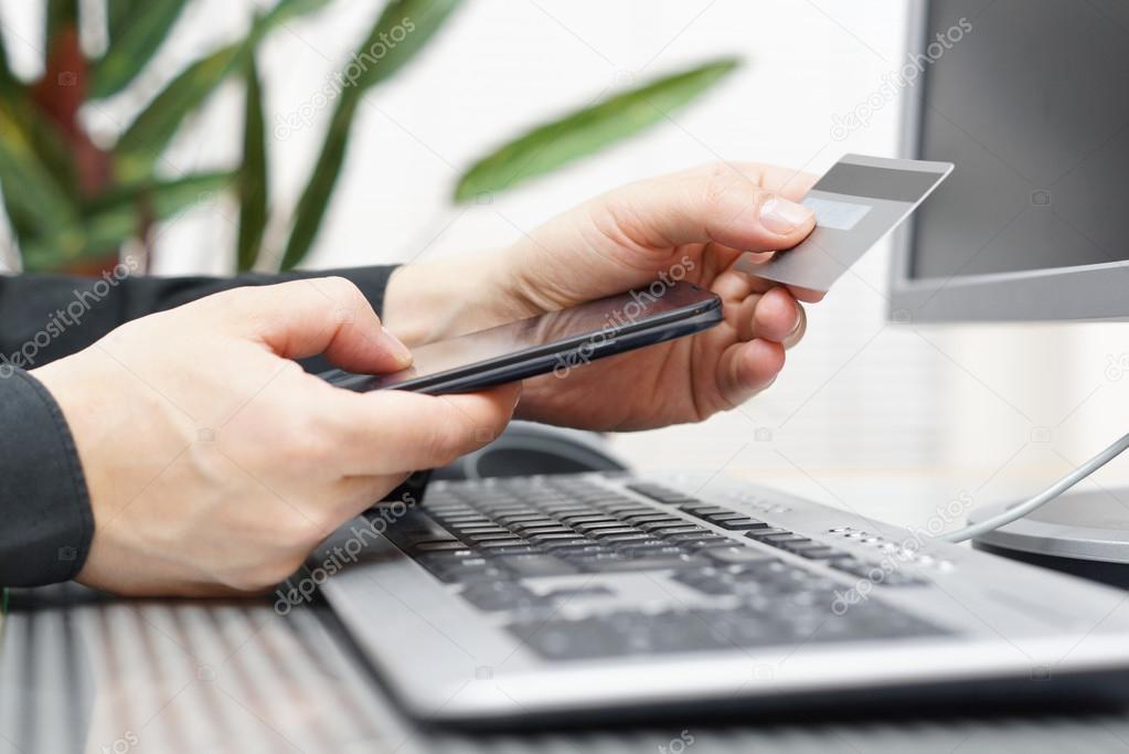 Man is using credit card and mobile phone for  on line payment.