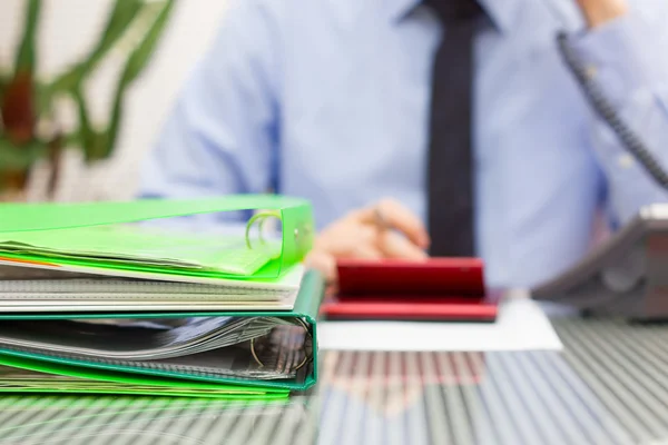 Overloaded consultant in blur with stack of binders and speaking — Stock Photo, Image