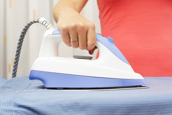 Vrouw hand strijken shirt op strijkplank — Stockfoto