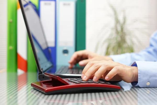 Uomo d'affari con pieno di raccoglitori e cartelle sta lavorando su lapto — Foto Stock