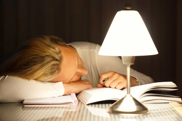 Terwijl leren viel de vrouw in slaap op de tafel — Stockfoto