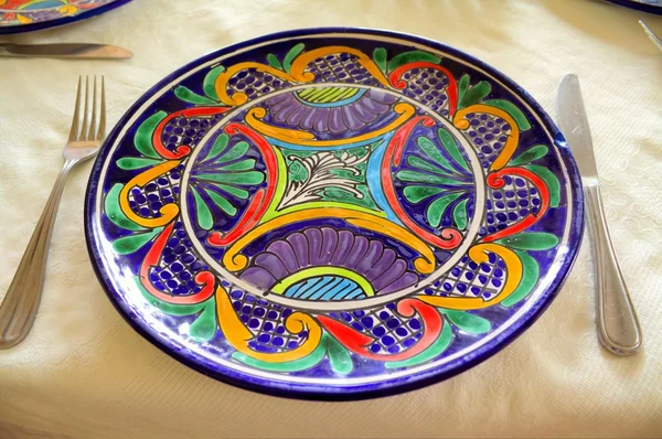 A Painted Plate and Silverware on a silk Tablecloth