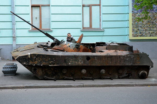 KYIV, UKRAINE - MAY 02, 2022: A man examines a destroyed Russian tank standing on the roadside, it was destroyed by the Ukrainian military in the Kiev region. Russia invaded Ukraine on February 24, 2022