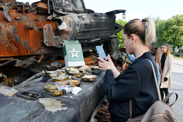 KYIV, UKRAINE - 23 Mayıs 2022: Bir kadın, Kyiv 'in Mykhailivska Meydanı' nda sergilenmekte olan bir Rus tankı üzerindeki askeri paketi fotoğraflıyor. Rusya 24 Şubat 2022 'de Ukrayna' yı işgal etti.