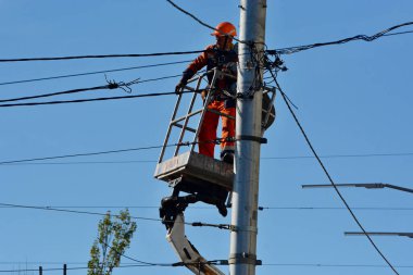 Bir elektrikçi, 10 Ekim 2022 'de Ukrayna' nın başkenti Kyiv 'de bir füzenin düştüğü Taras Shevchenko Ulusal Üniversitesi yakınlarındaki caddedeki Öğretmenler Evi' nin yanındaki iletişim ağlarını onarıyor..