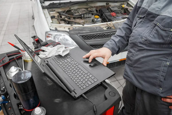 車の整備士は診断コンピュータの助けを借りて車を維持します 車の修理店で近代的な技術 修理ガレージで車のラップトップを使用した機械 — ストック写真